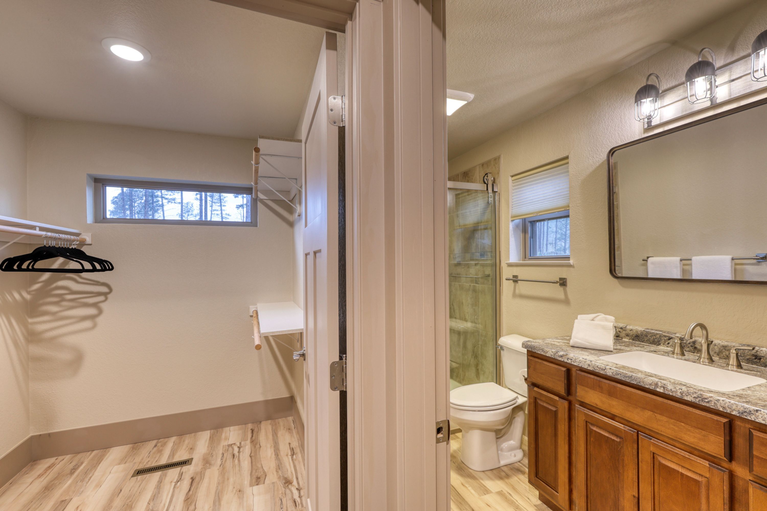 A bathroom with a shower, toilet, vanity, and a large mirror.