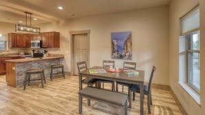 A modern kitchen with wooden cabinets, a central island, and a dining area with a table and chairs.