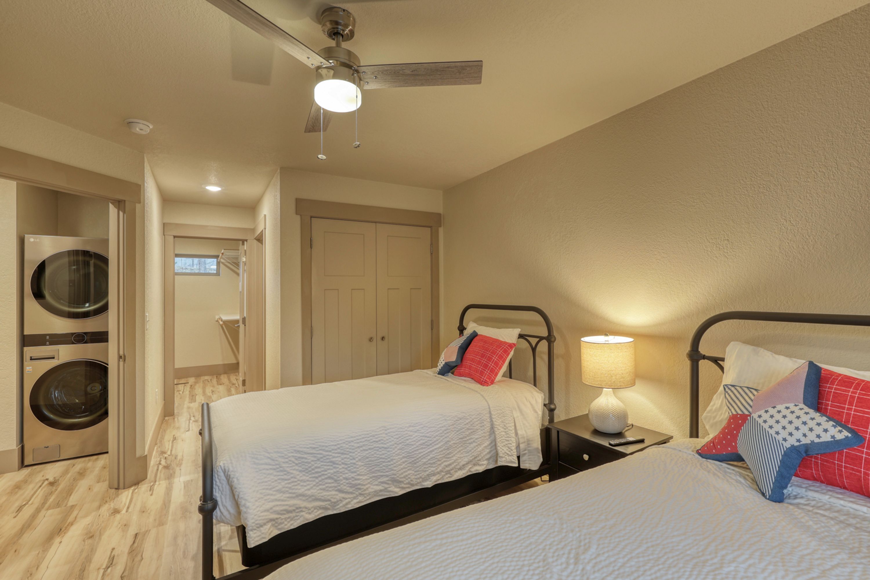 Habitación de hotel con dos camas, ventilador de techo, lavadora y lámpara.