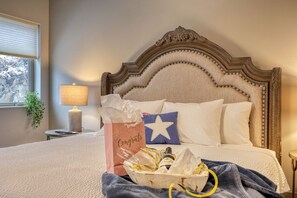 Un letto rifatto con cura, una testiera decorativa, una lampada da comodino, una confezione regalo e un cuscino a forma di stella.