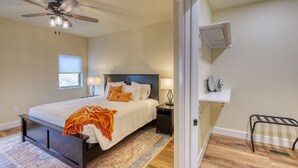 A bedroom with a bed, nightstands, a ceiling fan, a window, and a shelf with a drying rack. - Throttle Down in Style A Biker s Dream Stay (Rapid City)