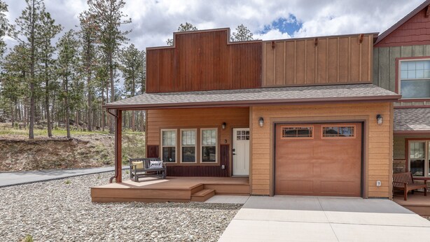 A modern two-story house with a garage, a covered porch, and a gravel driveway. - Throttle Down in Style A Biker s Dream Stay (Rapid City)
