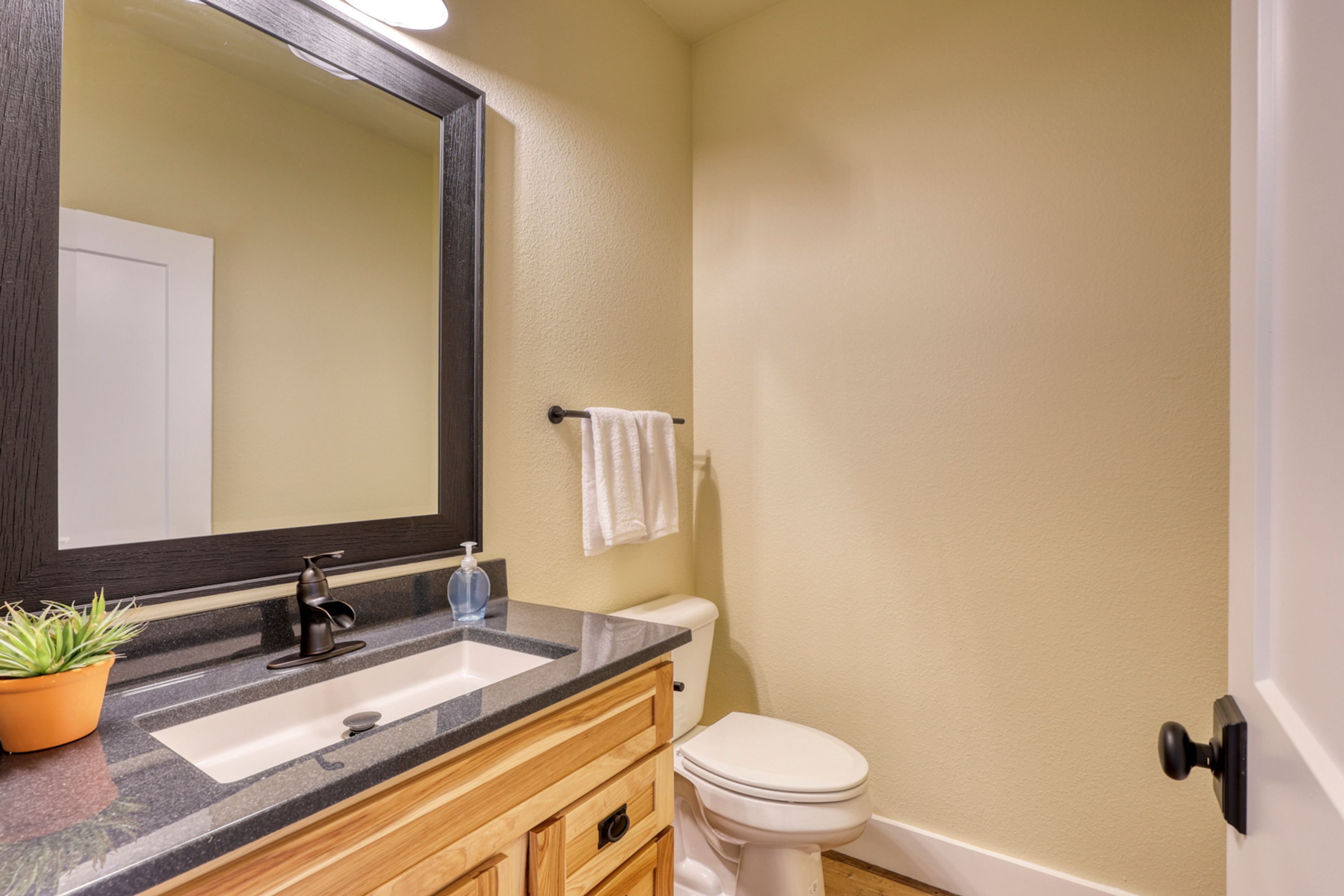 A bathroom with a sink, mirror, toilet, and towel rack.