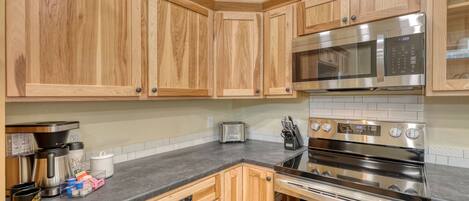 A kitchen with wooden cabinets, stainless steel appliances, a toaster, and a coffee maker.