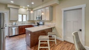 A modern kitchen with wooden cabinets, a stainless steel refrigerator, and a central island with stools. - Badlands Retreat Cozy Condo Modern Amenities (Rapid City)