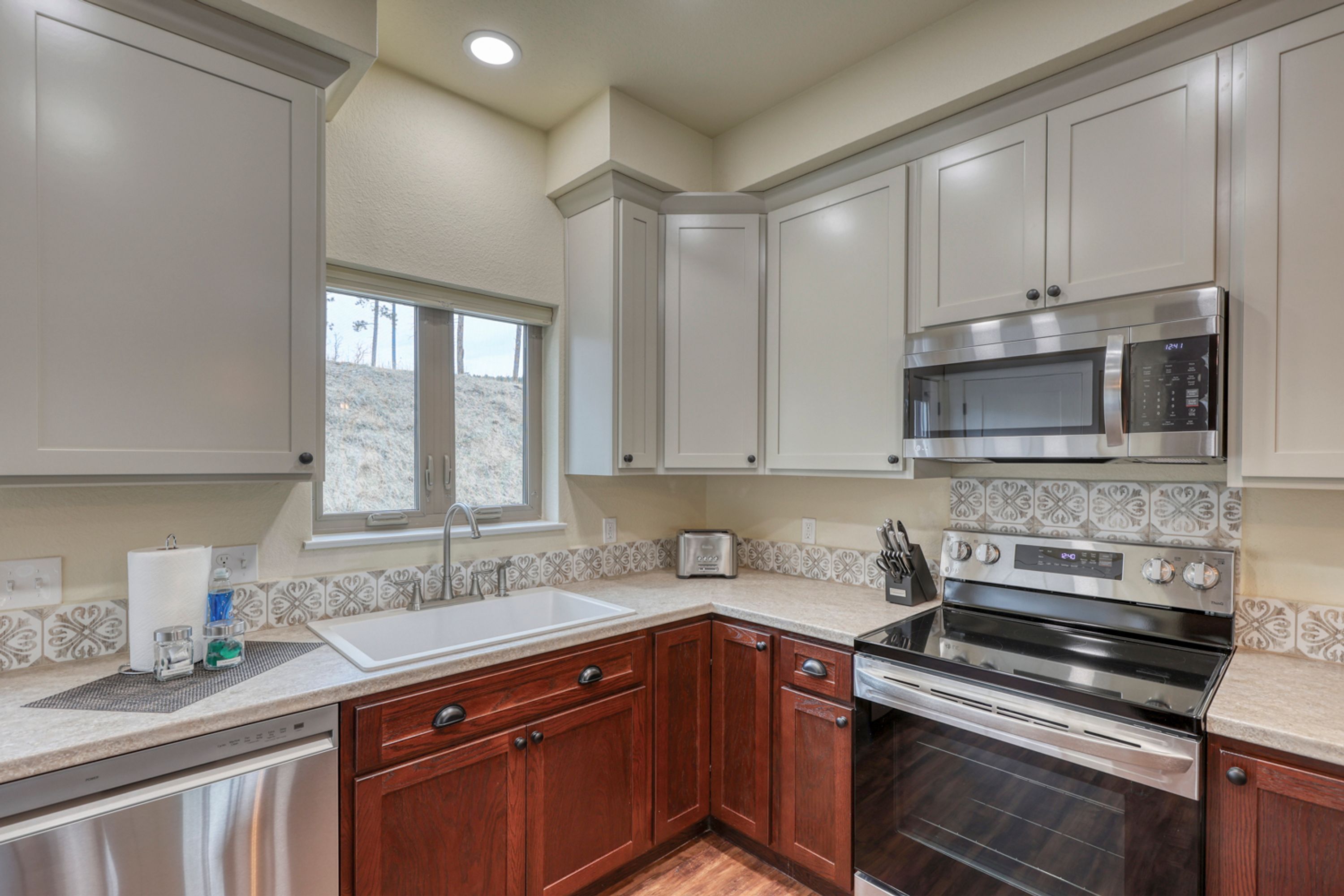 A kitchen with wooden cabinets, a stainless steel microwave, and an oven.