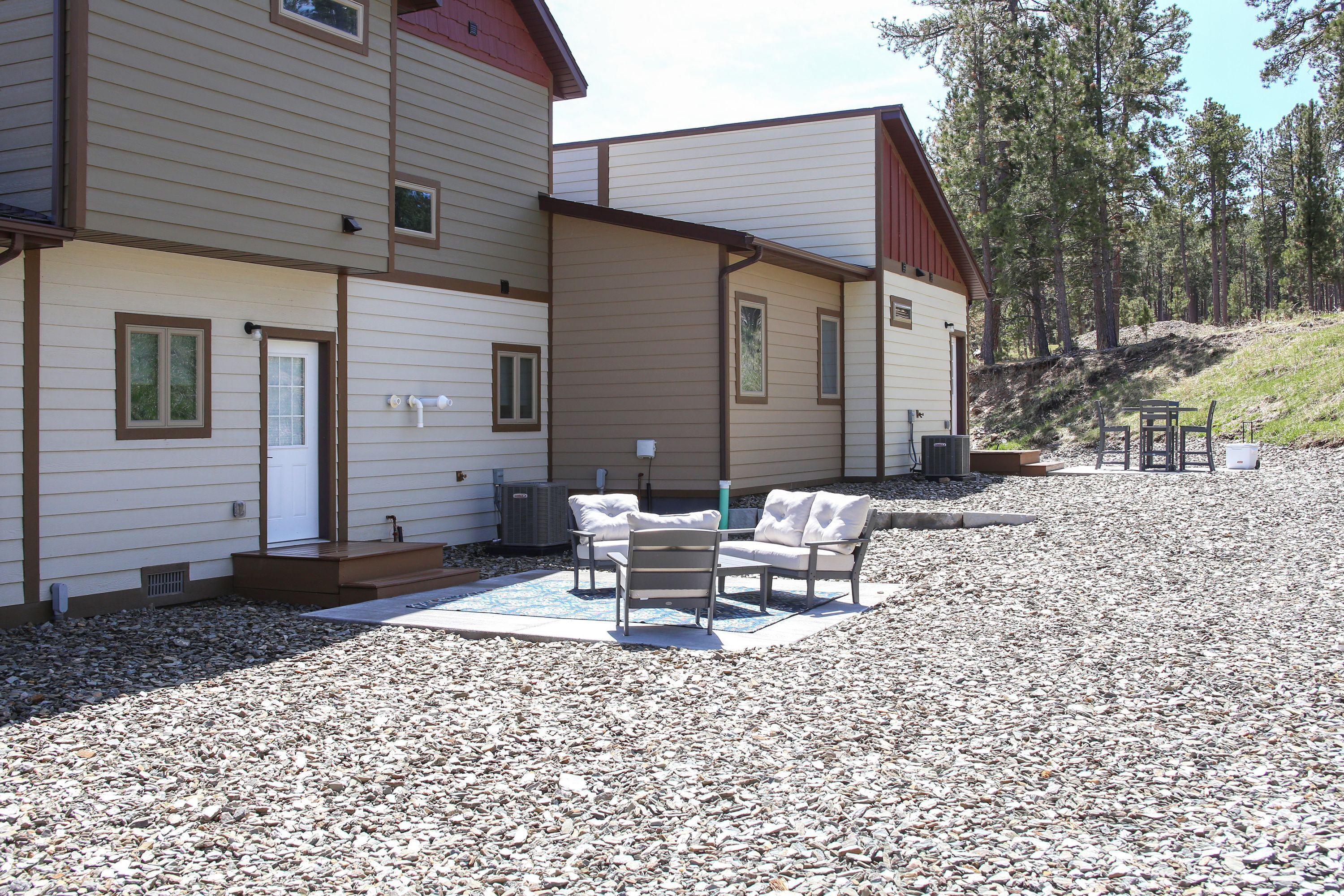 A two-story building with a covered patio area featuring outdoor furniture.