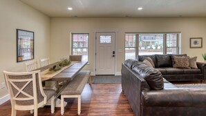 A dining area with a long table, chairs, and a bench. There is a brown leather sofa with cushions. - Badlands Retreat Cozy Condo Modern Amenities (Rapid City)