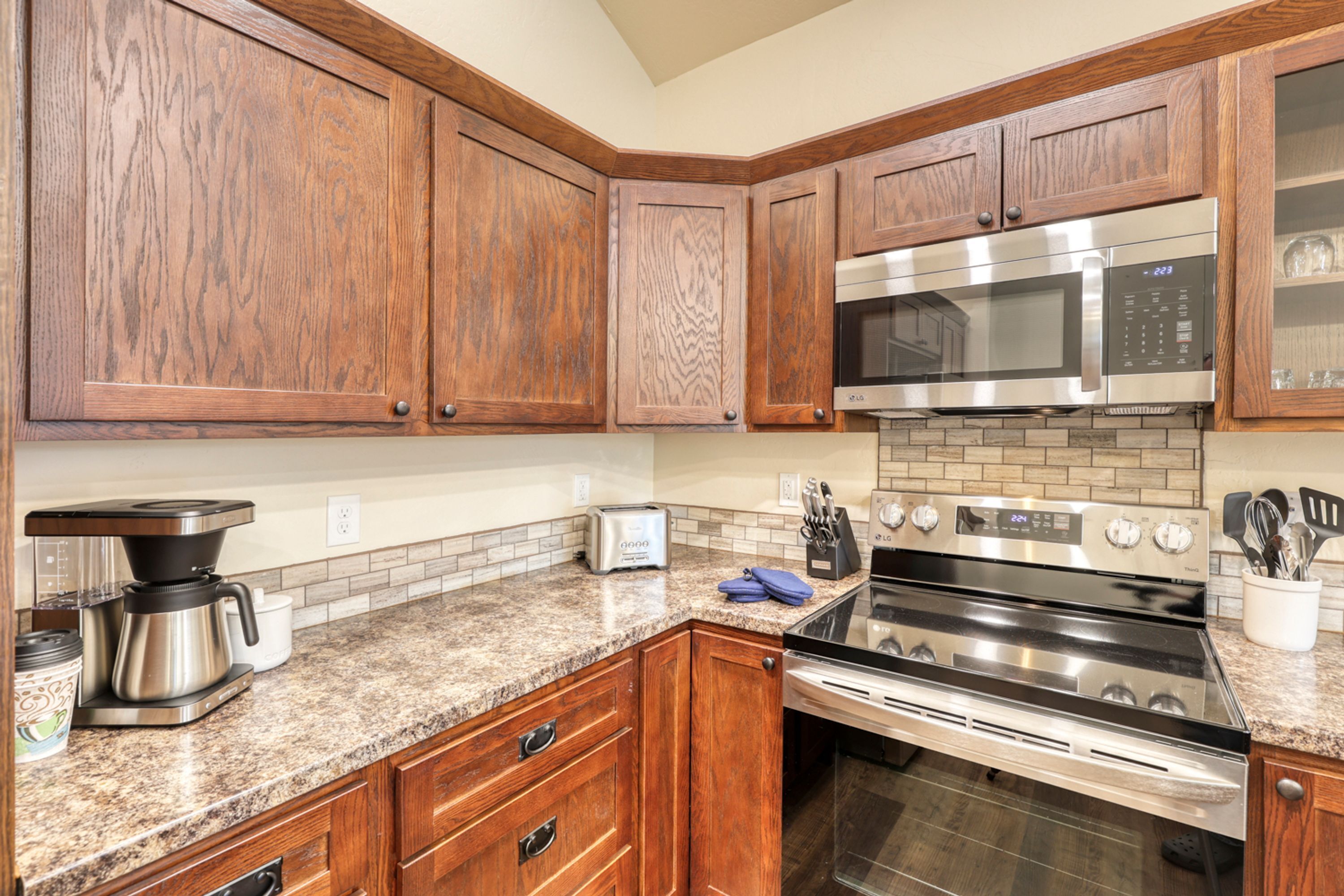 A kitchen with wooden cabinets, stainless steel appliances, granite countertops, and a built-in oven.