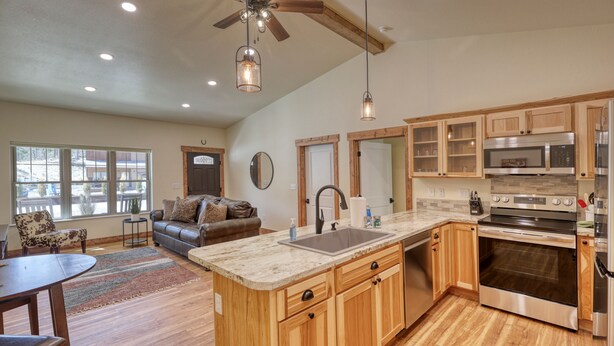 A spacious kitchen with wooden cabinets, a large island with a sink, and stainless steel appliances.
