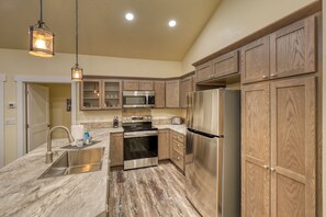 A kitchen with wooden cabinets, stainless steel appliances, a marble countertop, and pendant lighting. - Black Hills Retreat-hardrocker Haven (Rapid City)