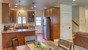 Una cocina amplia con armarios de madera, un refrigerador de acero inoxidable y un comedor con mesa y sillas.