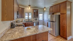 A kitchen with wooden cabinets, stainless steel appliances, and a marble countertop.