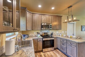 A modern kitchen with wooden cabinets, stainless steel appliances, and a marble countertop. - Modern Condo Near BH Attractions-garage Parking (Rapid City)