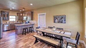 A spacious kitchen with wooden flooring, a central island, and a dining area with benches. - Modern Condo Near BH Attractions-garage Parking (Rapid City)