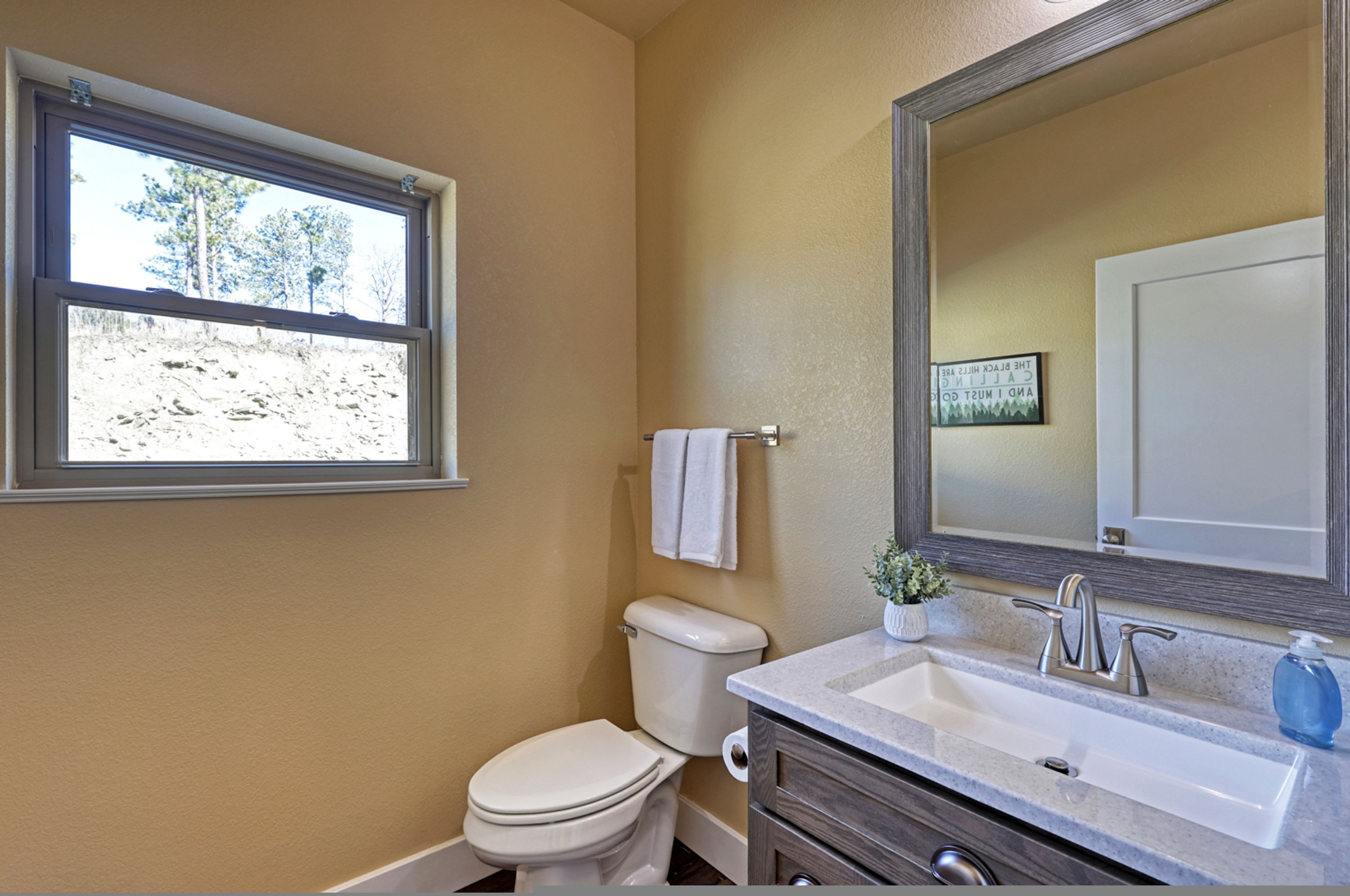 Un baño con inodoro, lavabo, espejo y ventana.