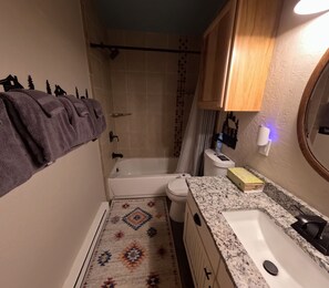 Un baño pequeño con bañera, inodoro y lavamanos.