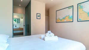 A hotel room with a large bed, a bathroom visible through an open door, and two maps on the wall. - L'escale d'Erquy - Proche Plage (Erquy)
