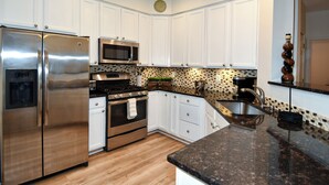 Een moderne keuken met witte kasten, roestvrijstalen apparatuur en een patroon backsplash.