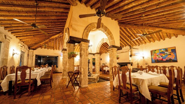 A restaurant with stone-tiled floors, wooden tables and chairs, and a high wooden ceiling with fans. - Rincon Del Montero (Parras de la Fuente)