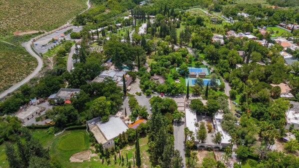 An aerial view of a residential area with multiple houses, a swimming pool, and a golf course.