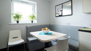 A small kitchenette with a window, a bowl of fruit on the counter, and a blue mat. - For Students Only Kimber Student Residence (Southampton)