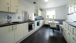 A modern kitchen with white cabinets, stainless steel appliances, and a black countertop. - For Students Only Kimber Student Residence (Southampton)