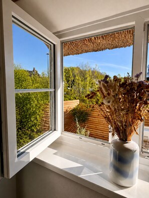 Une fenêtre donnant sur un jardin et une clôture en bois.