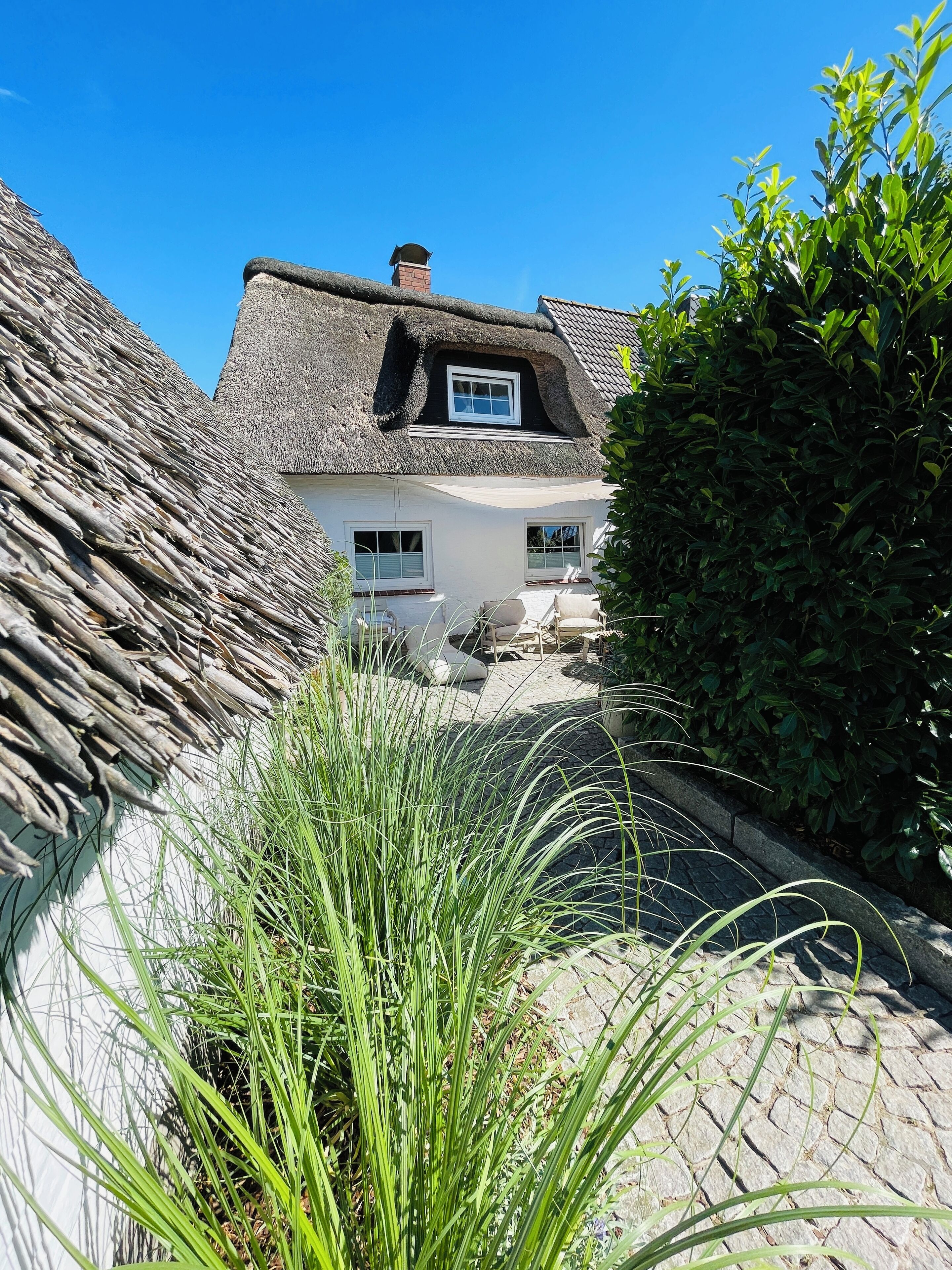 Une maison traditionnelle avec un toit de chaume, des murs blancs et une petite fenêtre.