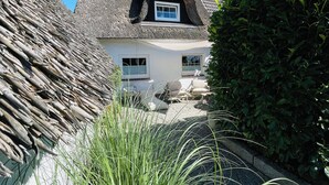 A traditional house with a thatched roof, white walls, and a small window.
