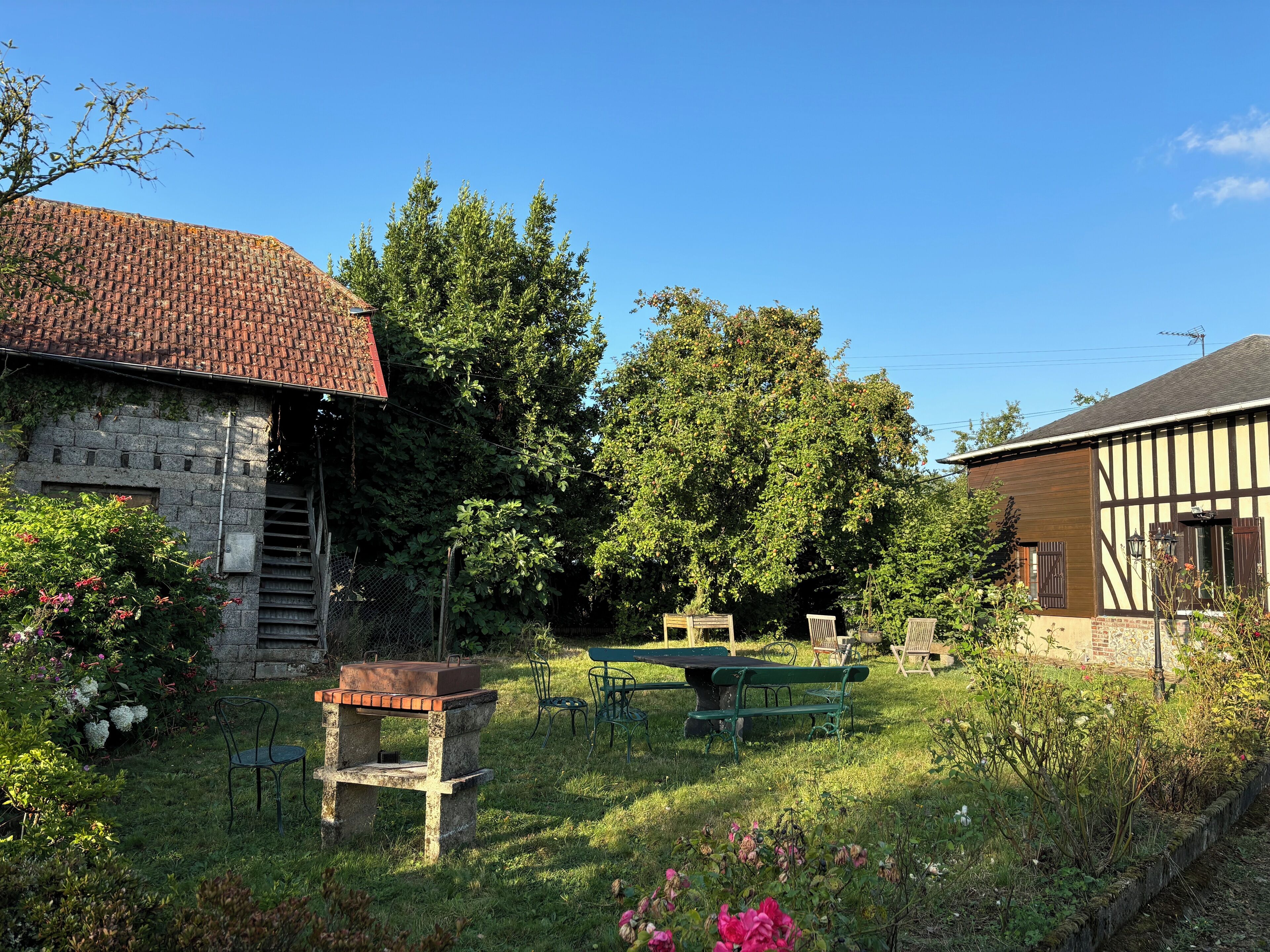 A rustic outdoor setting with a stone building, a wooden bench, and a table with a suitcase.
