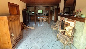 Une cuisine spacieuse avec des meubles de rangement en bois, un coin repas avec des chaises et une cheminée.