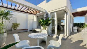 A modern outdoor patio with a round table and white chairs, surrounded by potted plants. - WhereInRio 4 suites luxury penthouse Ipanema (Rio de Janeiro)