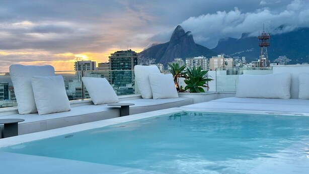 A rooftop pool with white lounge chairs and a cityscape view in the background. - WhereInRio 4 suites luxury penthouse Ipanema (Rio de Janeiro)
