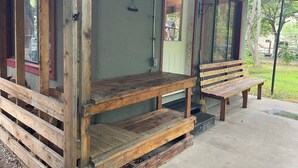 Een rustiek houten veranda met een bankje, een deur en een raam.