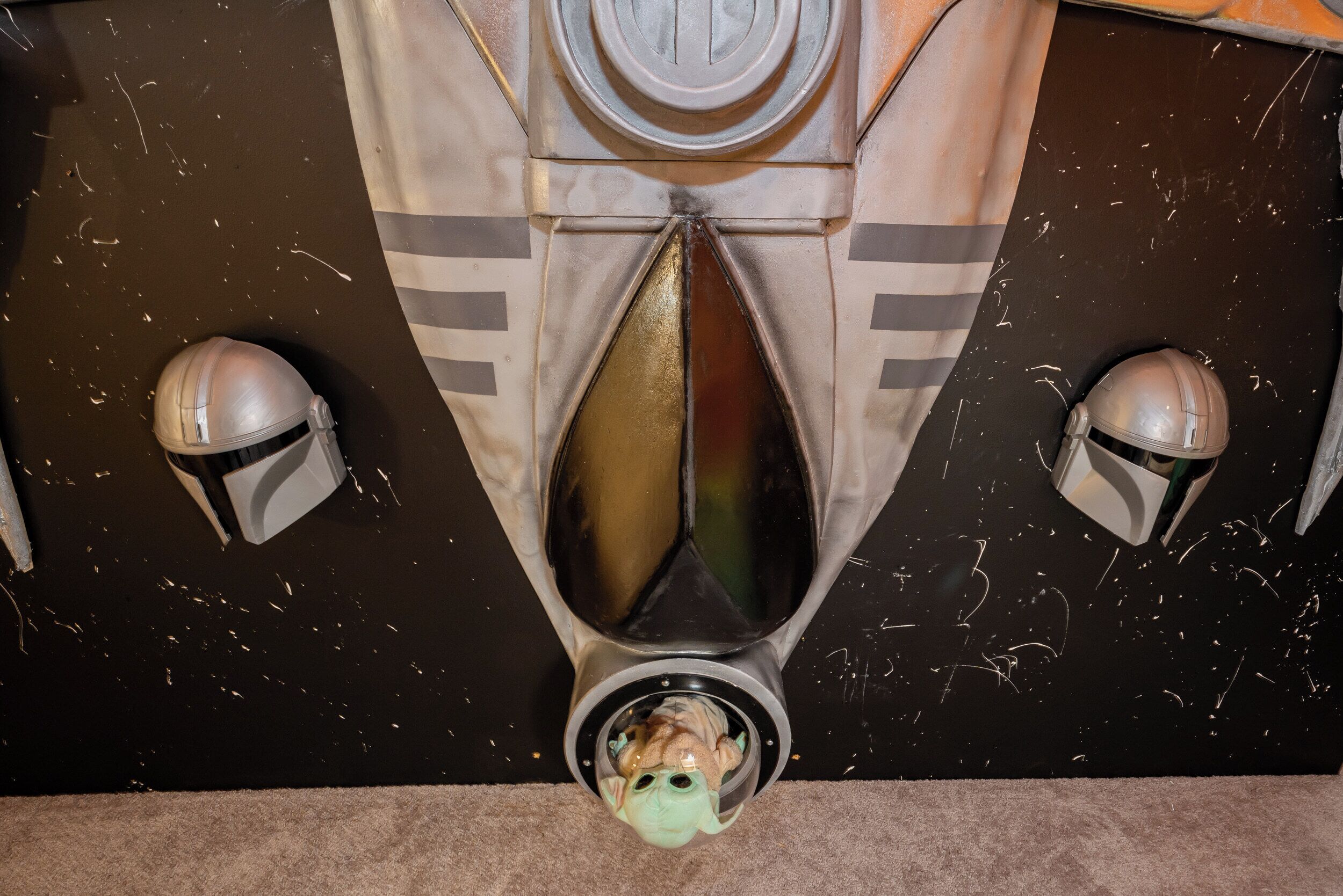 Quarto com decoração temática de Star Wars, incluindo um adorno no teto em formato de capacete e um emblema circular central.