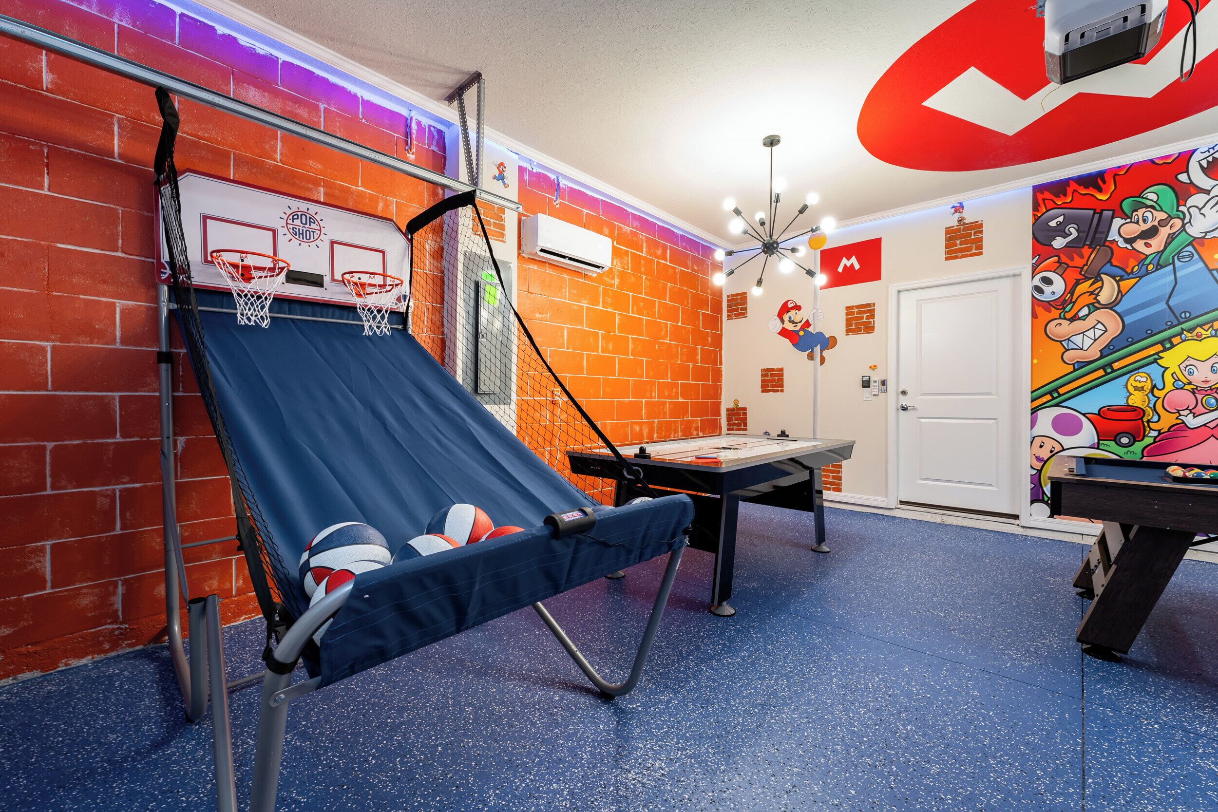 Een kamer met een basketbalveldje, een trampoline en een muurschildering met Mario thema.