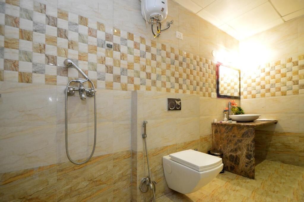 A bathroom with a checkered tile wall, a toilet, a sink, and a shower.