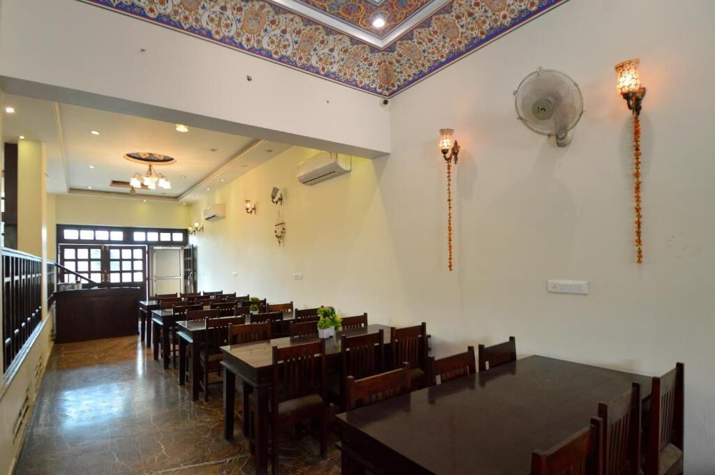 Un comedor amplio con varias mesas y sillas, un techo decorativo y lámparas fijadas a la pared.