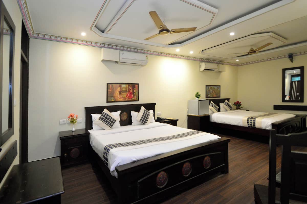 Une chambre d’hôtel avec un grand lit, deux tables de chevet, un ventilateur de plafond et un miroir au mur.