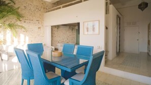 A dining area with a glass table and blue chairs, a white wall with a map, and a ceiling fan. - Cozy Renovated Apt with Delightful View/Old City (Cartagena de Indias)
