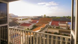 A balcony with a view of a residential area, featuring buildings with red and grey roofs. - Cozy Renovated Apt with Delightful View/Old City (Cartagena de Indias)