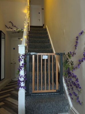 En trappe med en trälåge, lilla blommor och en skylt på väggen.
