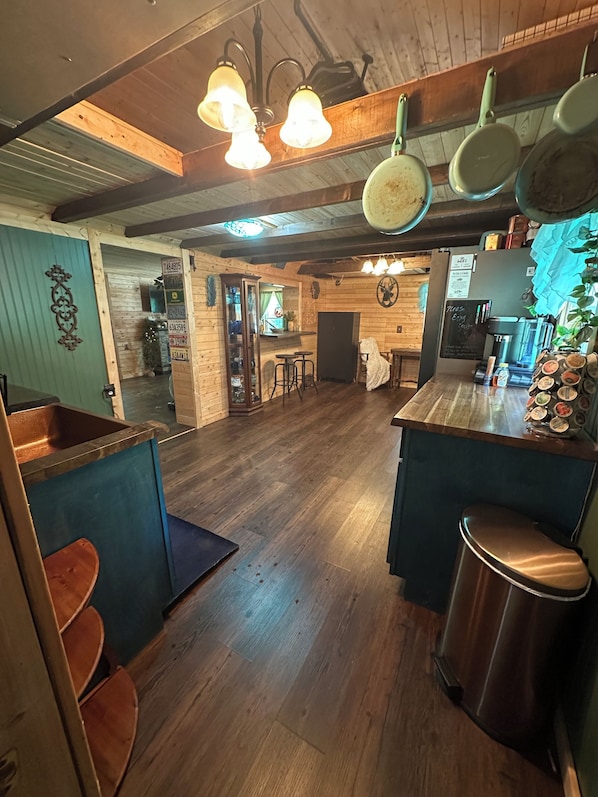 Una cocina rústica con pisos de madera, ollas colgantes y una barra con taburetes.