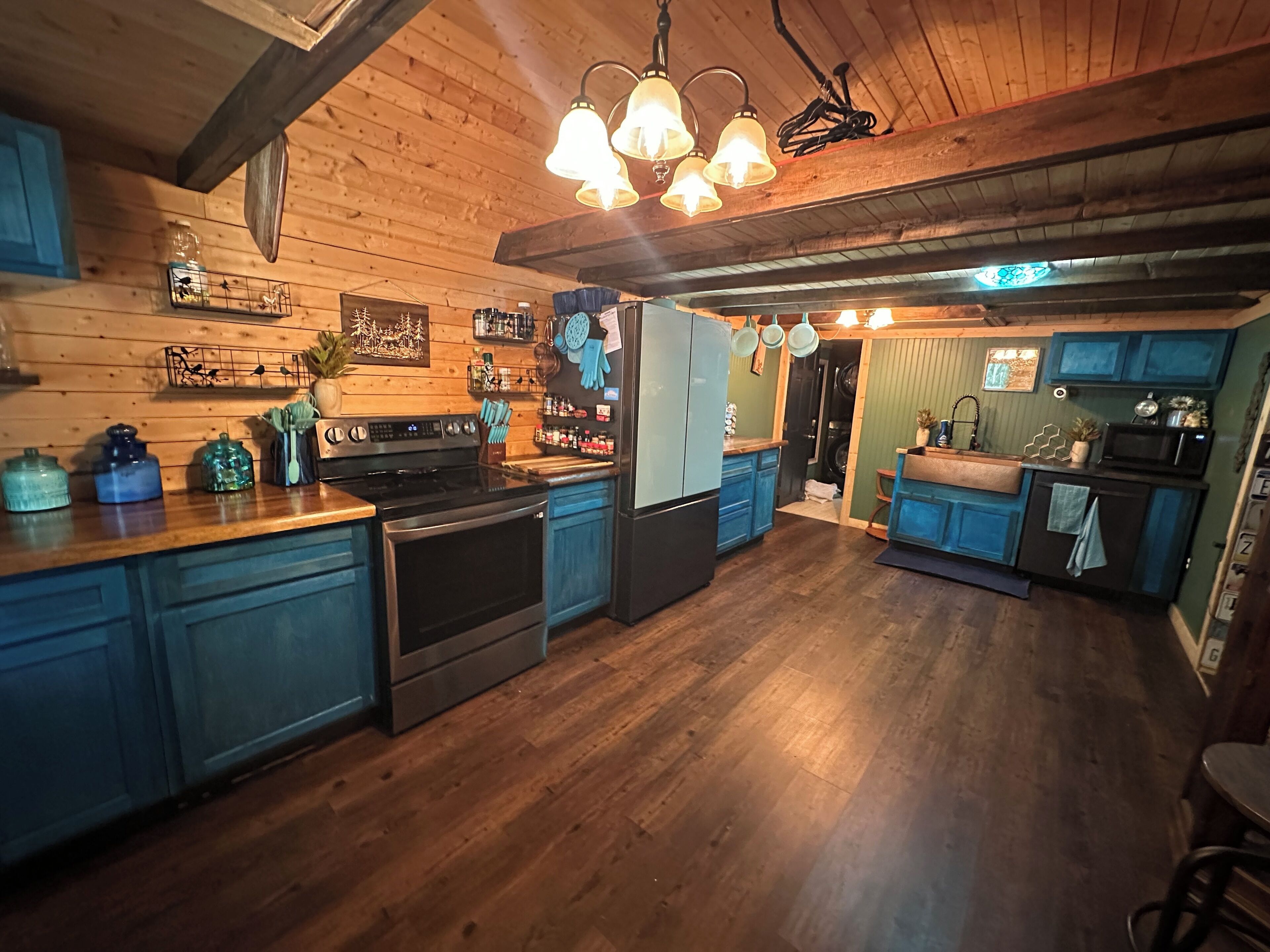 A kitchen with wooden cabinets, a stove, and hanging lights.