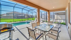 Una veranda esterna coperta con piscina, barbecue e zona salotto.