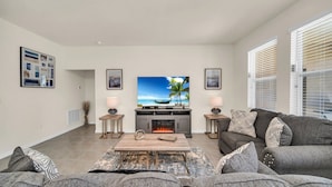 A living room with a flat-screen TV, fireplace, grey sofa, and a coffee table. - Magical Family Getaway 7BD Villa with (Davenport)