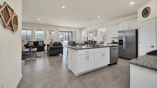 A spacious kitchen with white cabinets, a stainless steel refrigerator, and a large island. - Magical Family Getaway 7BD Villa with (Davenport)