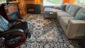 Un salon chaleureux avec une cheminée, un canapé, un tapis à motifs et un téléviseur.