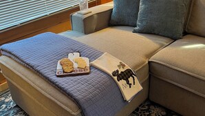 Une pièce confortable avec un canapé-lit, une couverture, un plateau de collations et un coussin décoratif.